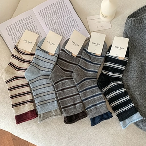 Gros plan de cinq paires de chaussettes vintage à rayures avec bords roulés contrastés et emballages