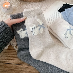 Detail of thick knit crew socks with cute flocked cat pattern and bow accents