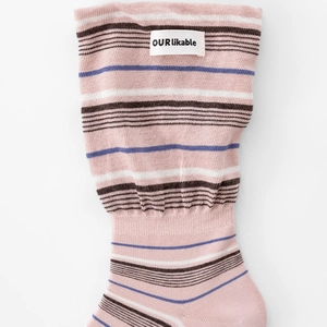 Détail de chaussettes rayées roses avec texture côtelée et étiquette tissée 'OUR likable'