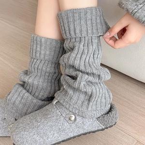 Close-up of grey ribbed knit leg warmers paired with cozy felt mule slippers