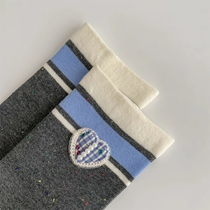 Detail of grey confetti knit socks with blue heart patch and pearl embellishments