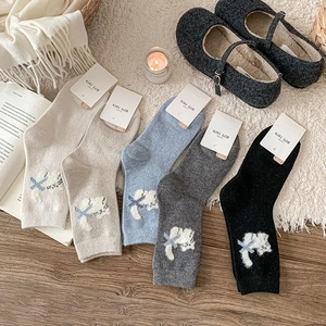 Close-up of knit crew socks with cute 3D plush cat embroidery and velvet bow detail