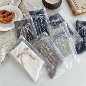 Flat lay of colorful mid-calf socks with bows and lace edges in individual zipper bags