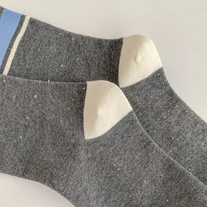 Close-up of collegiate gray knit socks with confetti yarn and light blue striped cuffs
