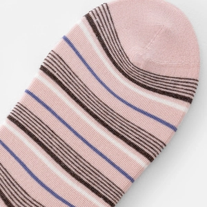 Détail de chaussettes en maille rose avec rayures fines marron, blanches et bleues