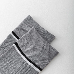 Close-up of gray knit socks featuring black and white stripe detailing and fine texture