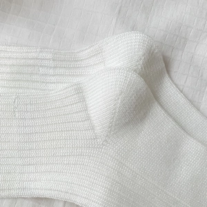 Detailed close-up of white ribbed knit ballet style socks with fine vertical stripe texture