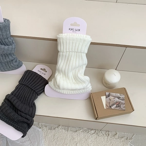 Detail of ribbed knit leg warmers in white and grey, showing texture and soft material
