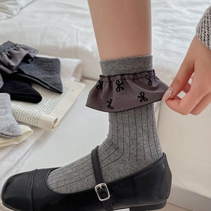Detail von grauen Rippsocken mit Schleifendruck und Rüschensaum zu Mary Jane Schuhen