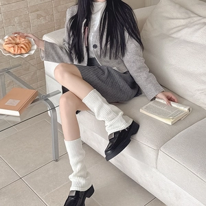 Minimalist white ribbed knit leg warmers paired with skirt and leather shoes