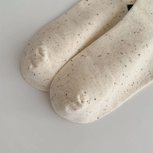 Close-up of beige knit socks featuring colorful nep yarn texture and fine toe stitching
