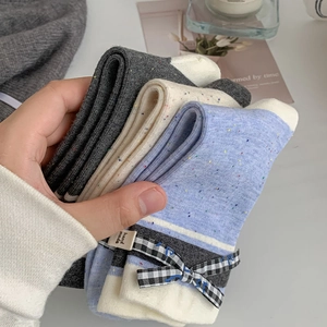Detail of color-flecked knit socks with plaid bows and hand-made label tags