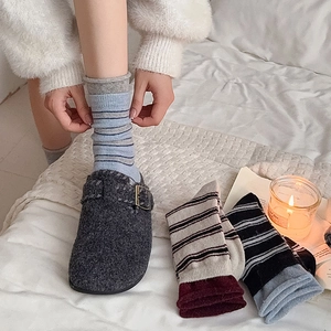 Détail de chaussettes rayées vintage avec des chaussons en feutre gris en scène douillette
