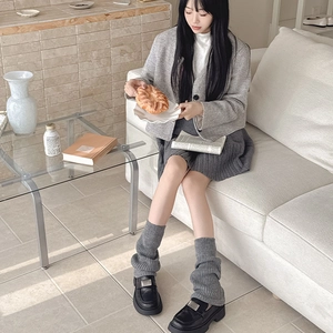 Detailed texture of thick dark grey ribbed knit leg warmers paired with black leather loafers