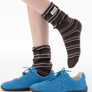Gros plan de chaussettes marron rayées avec étiquette blanche et baskets en daim bleu