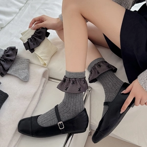 Details von Socken im Ballett-Stil mit Rüschenrand und schwarzen Schleifen auf Rippstrick