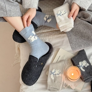 Detail of soft knit mid-calf socks with cute cartoon cat patterns and blue bow accents