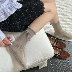 Detail of beige ribbed crew socks featuring vintage plaid bow and ruffled edge trim