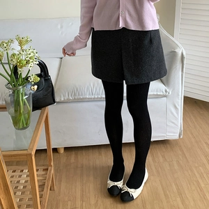Close-up of women's black vertical stripe knit tights worn with grey wool skirt