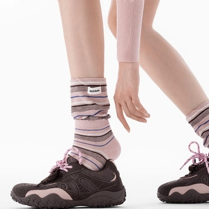 Gros plan de chaussettes mi-mollet à rayures roses avec étiquette et baskets vintage