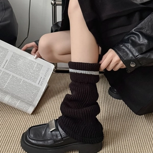 Close-up of ribbed knit leg warmers with grey stripe detail and loafers