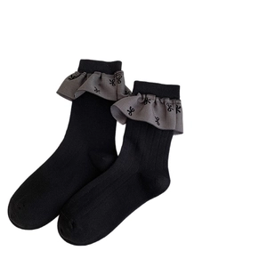 Gerippte Ballettsocken mit grauen Rüschen und Schleifenverzierung auf schwarzem Stoff