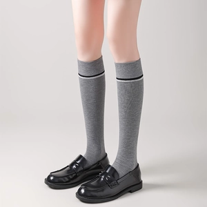 Close-up of grey knee-high socks with striped cuffs and black patent leather loafers