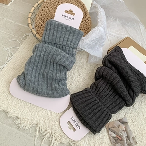 Detailed close-up of ribbed knit texture on grey leg warmers with folded cuffs
