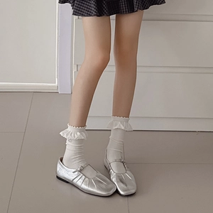 Scarpe Mary Jane argento con calze a balze bianche su sfondo minimalista