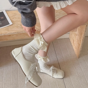 Detailaufnahme weißer Spitzensocken mit Schleife und flachen Lolita-Schuhen mit Band