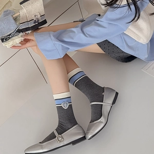 Close-up of knit crew socks with blue stripes and heart embroidery detail