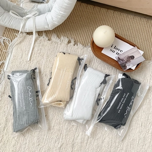 Four pairs of ballet style bow socks in assorted colors with frosted zipper packaging