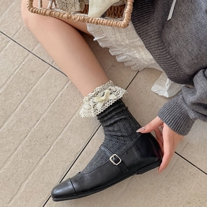 Detail von grauen JK-Socken mit weißem Spitzenbesatz und kleiner Schleife