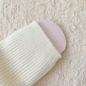 Macro shot of off-white ribbed knit leg warmers showing soft texture and vertical patterns