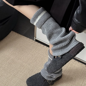 Detail view of grey ribbed knit leg warmers with white stripe accent and stacked texture