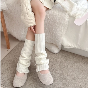 Detail of creamy white knitted leg warmer with thick vertical rib texture and split hem