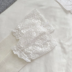 Detailed view of white lace trim cuffs with layered wave patterns and ribbed fabric texture
