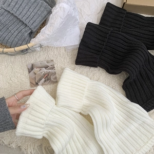 Macro detail of ribbed knit texture on thick leg warmers in black, white, and grey
