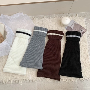 Chic striped knit leg warmers in cream, grey, brown, and black for winter fashion outfits