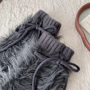 Detail of dark grey faux fur leg warmers with knitted cuffs and cute lace-up bows