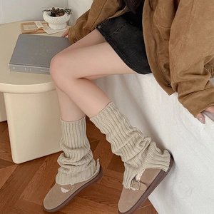 Close-up of beige ribbed knit leg warmers paired with stylish brown leather loafers