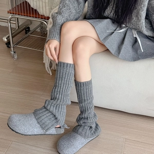 Detail of gray vertical striped knit leg warmers paired with casual felt slippers