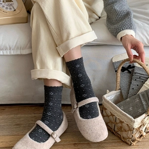 Detail of dark grey crew socks with floral patterns paired with Mary Jane shoes