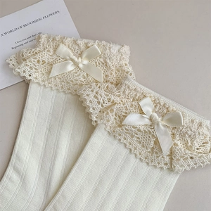 Detailansicht von cremefarbenen Rippstricksocken mit weißer Spitze und Satinschleife