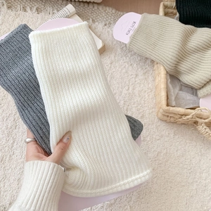 Detail of ribbed knit leg warmers in various colors with soft texture and brand packaging