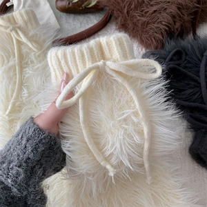 Detail of furry leg warmers with knit ribbed cuffs and decorative bows in white, brown and grey