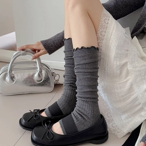 Close-up of gray ribbed leg warmers with delicate ruffle edges for a balletcore style