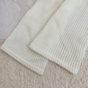 Close-up of cream knit leg warmer showing vertical rib texture and soft fabric detail