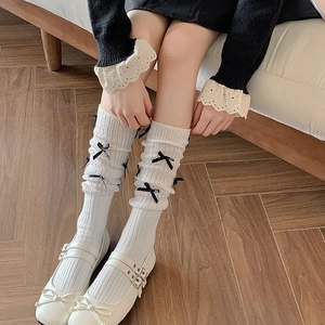White rib-knit balletcore leg warmers with black ribbon bows for a sweet aesthetic