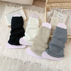 Winter knitted leg warmers in four colors with vertical stripes on white carpet